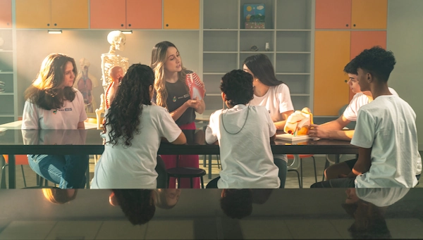 Imagem de uma professora e os alunos na sala de biologia